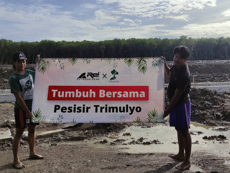 Anggota TRIPARI memegang banner LindungiHutan x Arei Outdoor Gear di Trimulyo.
